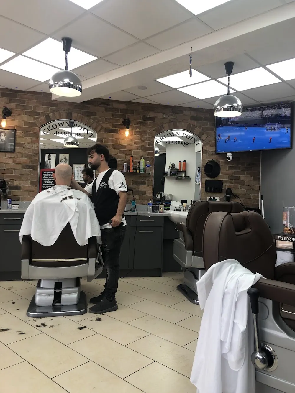A barber at work on a client inside Crown Point Barbers